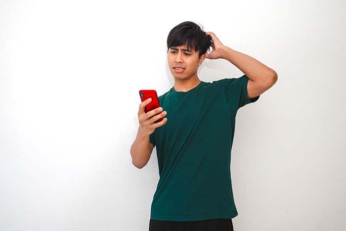 A man looking at his phone and seeing his trading account declining.
